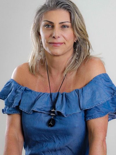 Woman in blue off-shoulder top with necklace, smiling softly.