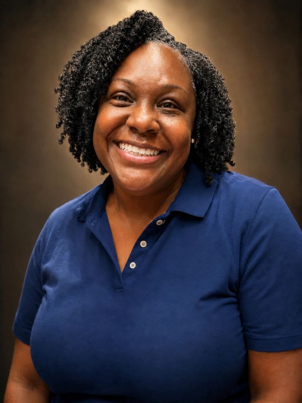 Smiling woman with curly hair wearing a blue polo shirt.