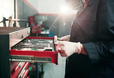 Person wearing gloves opening a toolbox drawer.