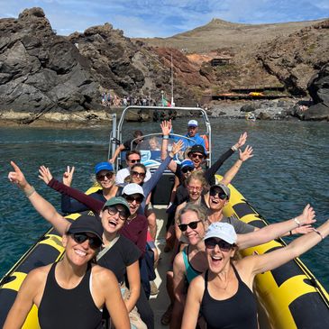 Group of friends enjoying a boat ride in clear waters near rocky cliffs.