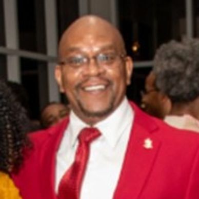 Man in a red suit smiling at a social event.
