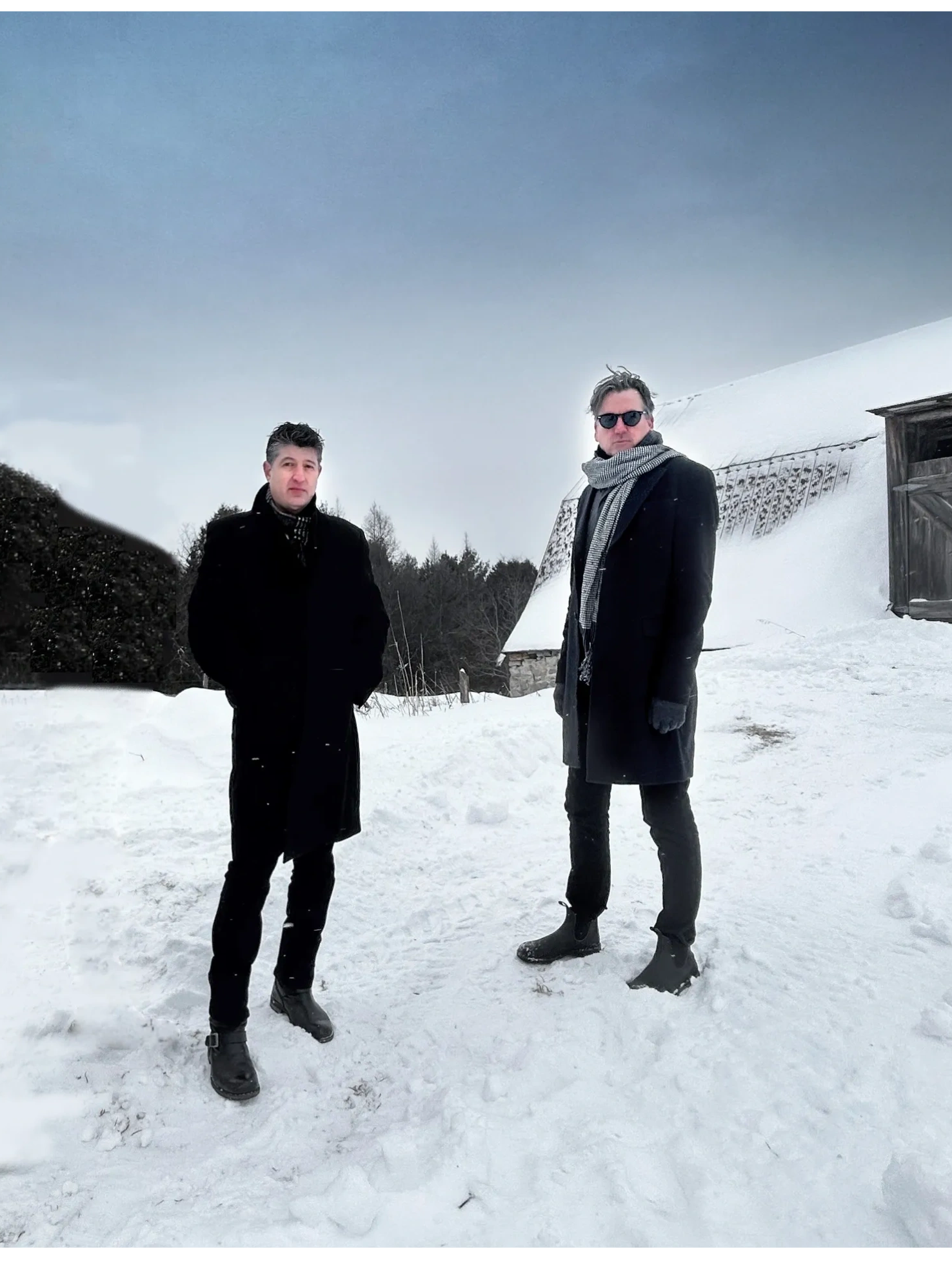 Photo of Jason and Paul from THE 12th MAN standing outside a barn in the snow in  a Canadian Winter.