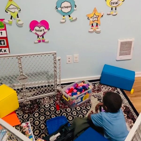 Child playing in a colorful educational playpen with shape cutouts on the wall.
