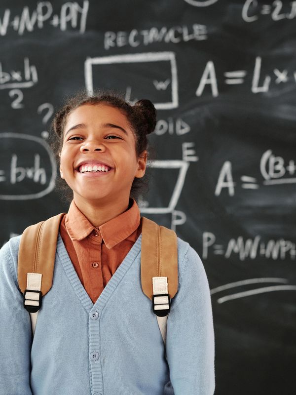 Smiling student standing in front of a math-filled chalkboard.
