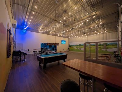 Indoor recreational space with pool table and seating under string lights.