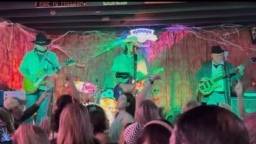 Band performing live on stage with crowd dancing.