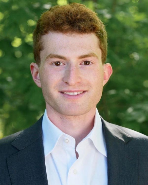 Young man in a suit smiling outdoors.