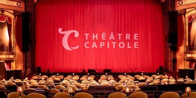 Interior view of Théâtre Capitole with red curtain and vintage seats.