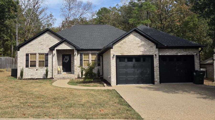 Light brick home with dark garage doors