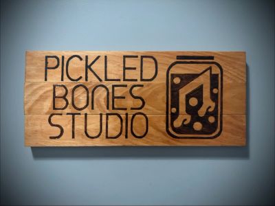 Wooden sign for Pickled Bones Studio with music jar graphic.