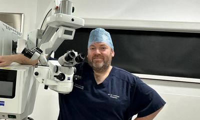 Doctor in surgical scrubs beside medical equipment.