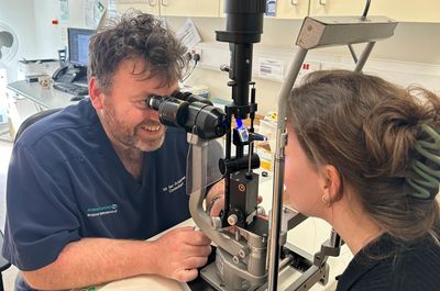 Eye doctor examining a patient's eye using a slit lamp.