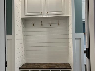 Finished mudroom with shiplap, bench, and coat hooks