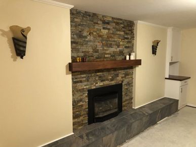 Remodeled fireplace wall with stacked stone and a poplar mantel