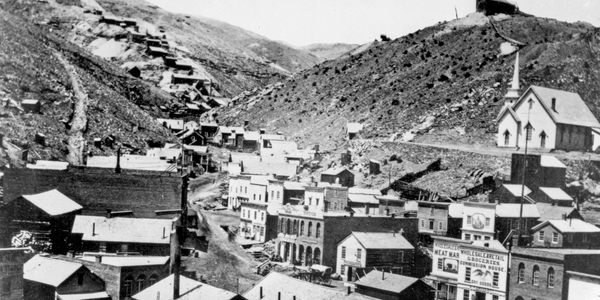 Historic western town with hillside buildings and a church.