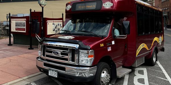 Maroon Black Hawk shuttle bus parked on the street.