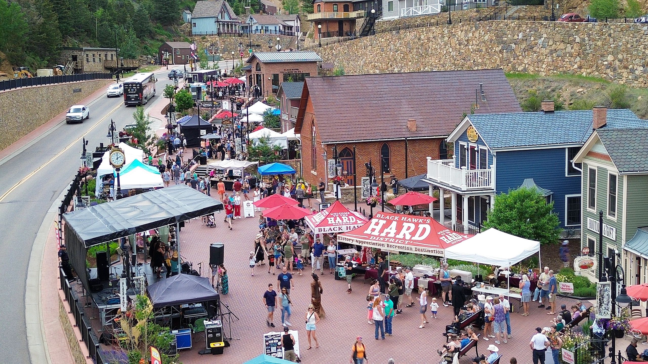 Crowded street festival with booths, tents, and people in a historic town.