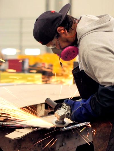 man using an angle grinder on a custom metal fabrication