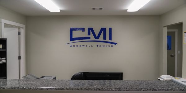 Reception area with CMI Cogswell Towing logo on wall and granite counter.