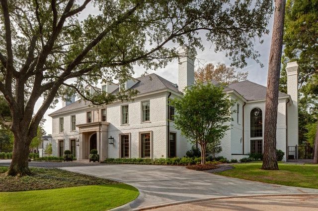 Large white two-story house with elegant architecture and lush greenery.