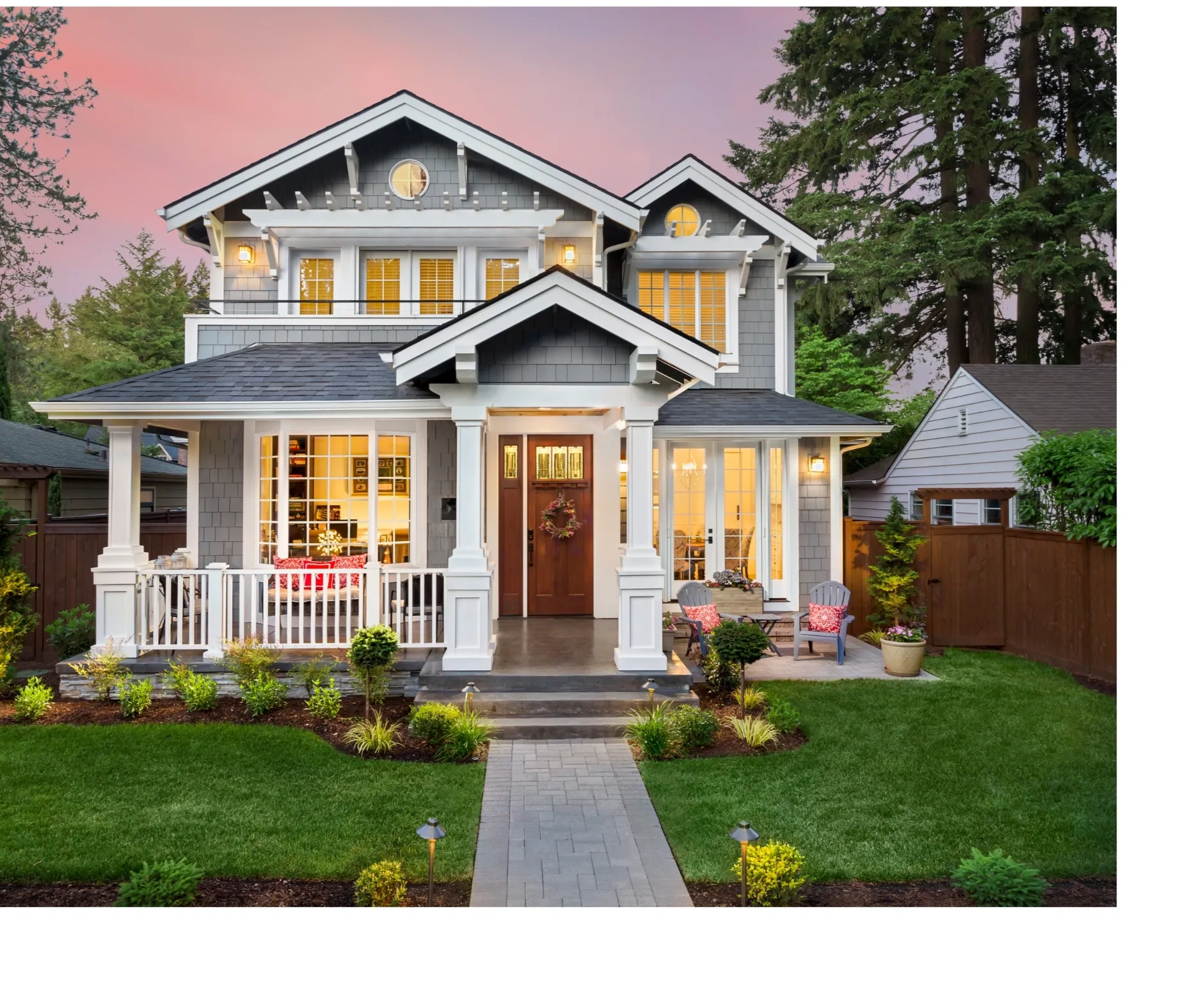 A charming two-story house at dusk with warm interior lighting and a welcoming front porch.