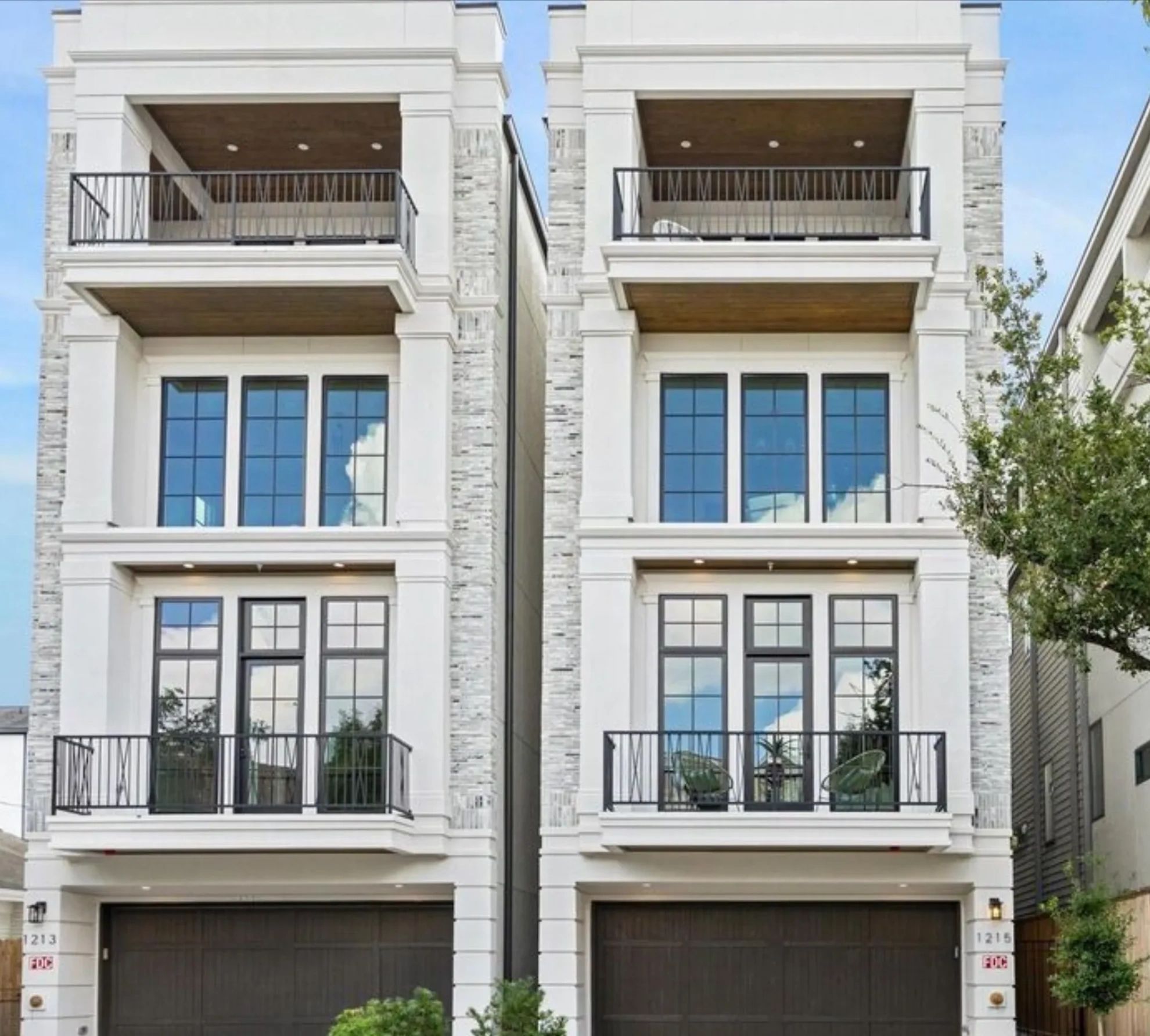 Modern twin townhouses with balconies and large windows.