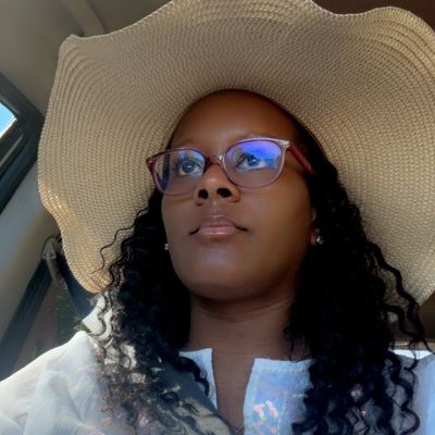 Woman wearing glasses and a large sunhat inside a car.