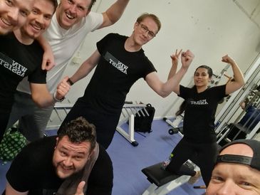 Group of friends flexing muscles in a gym.