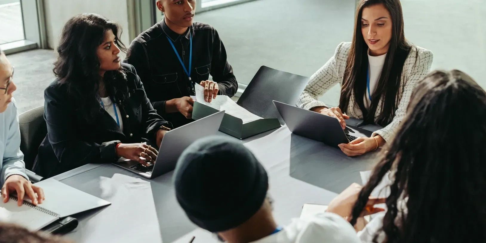 Group meeting with laptops around a conference table.