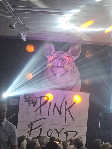 Giant inflatable pig with glowing eyes at a Pink Floyd concert stage.