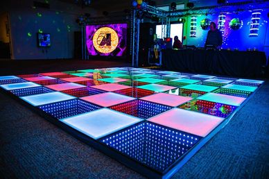 Colorful illuminated dance floor with mirrors and disco balls in a party setting.