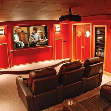 Cozy home theater with red walls and leather seats.