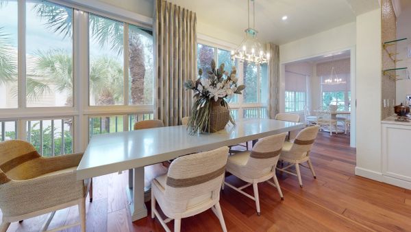 Elegant dining room with a large table, comfortable chairs, and a floral centerpiece under a modern chandelier.