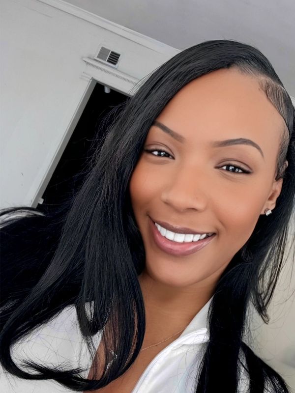 A woman with long black hair smiling brightly indoors.