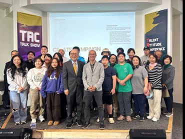 Group photo of diverse individuals at a talk show event with presentation screen.