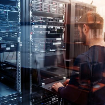 Technician working on a laptop in a server room.