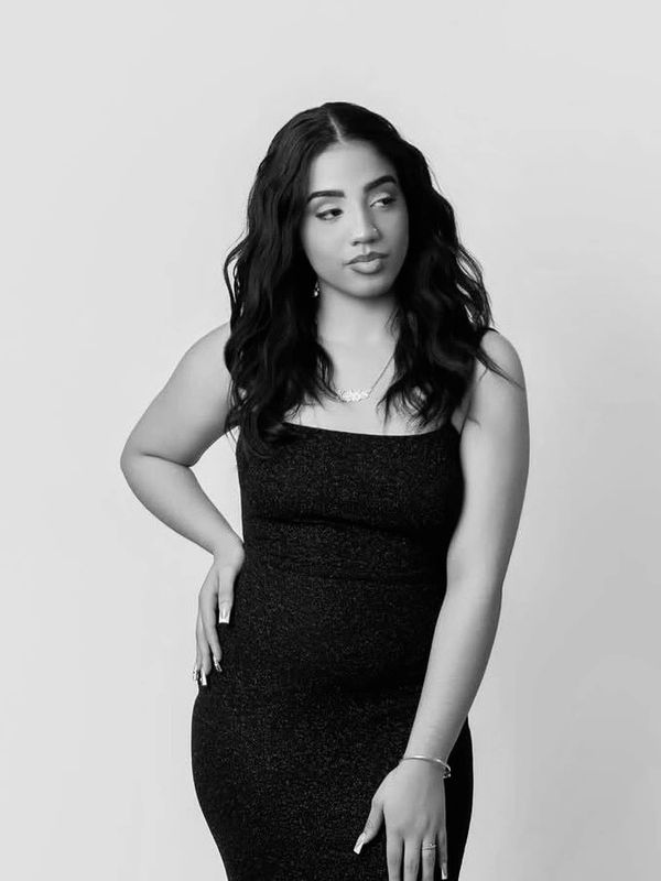 Woman in a black dress posing thoughtfully.