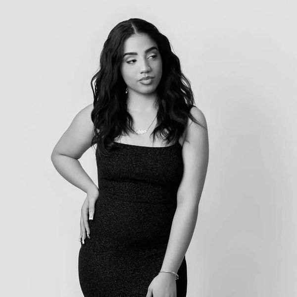 Woman in a black dress posing against a plain background.