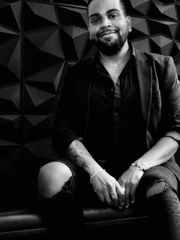 Smiling man sitting in front of a geometric wall.