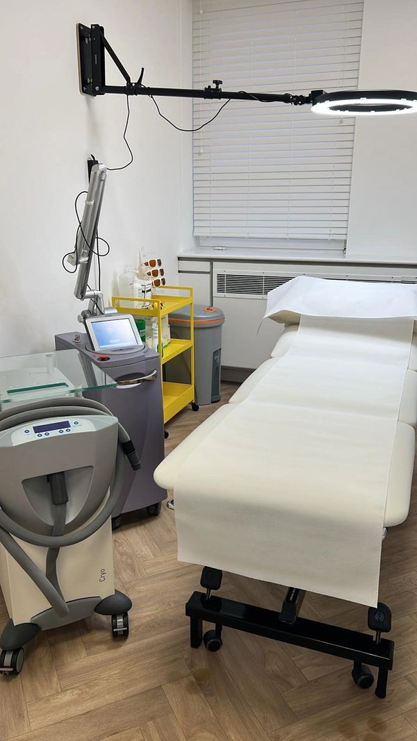 A clean medical or aesthetic treatment room with equipment and a treatment bed.