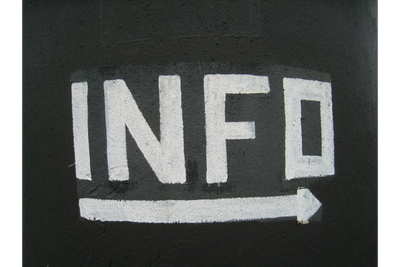 White painted 'INFO' text with an arrow on a dark wall.