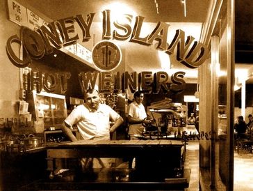 Vintage Coney Island hot dog stand with two workers inside.