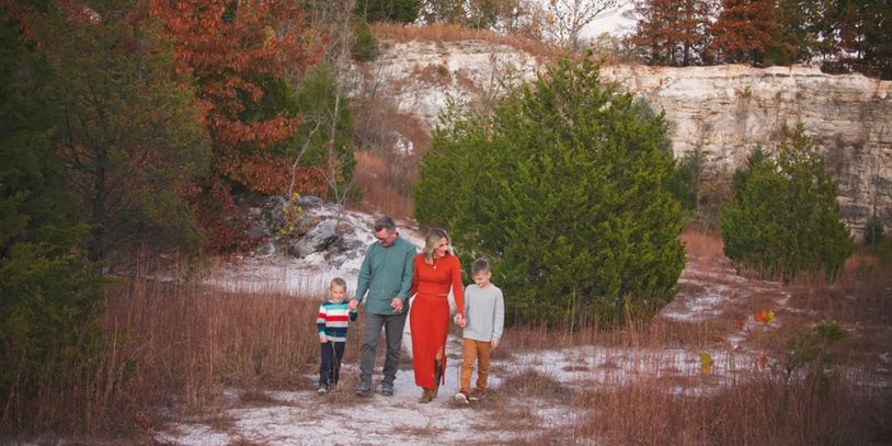 Family of four walking in autumn landscape.