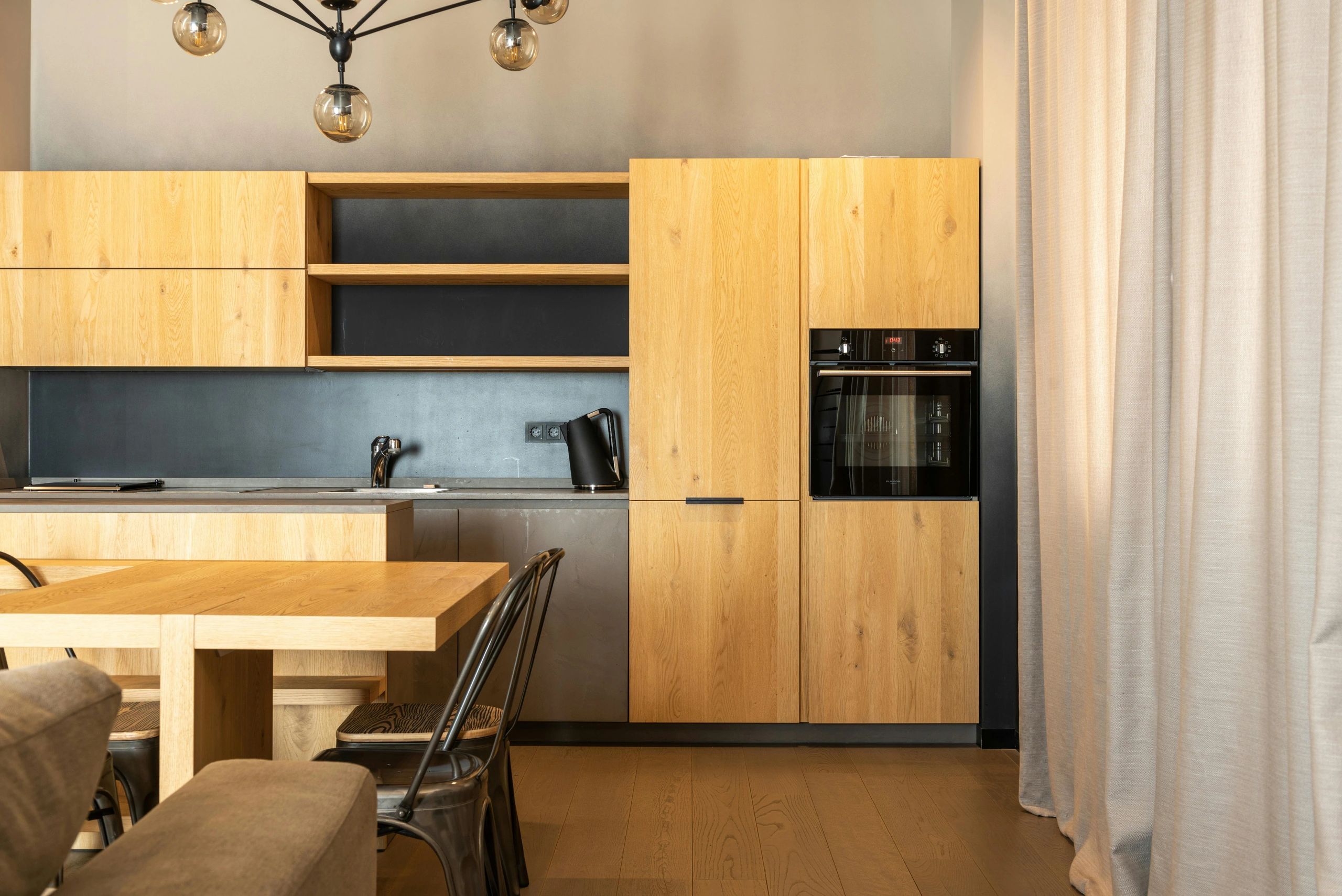 Modern kitchen with wooden cabinets, black backsplash, and a built-in oven.