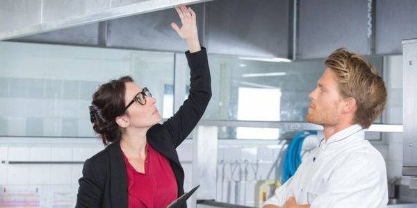 Woman inspecting ceiling with man watching.