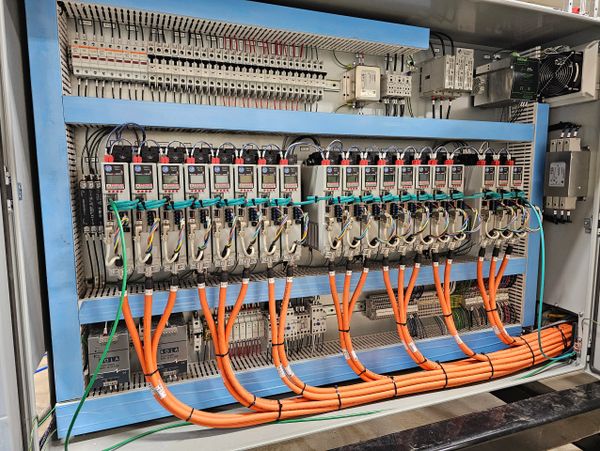 Organized electrical control panel with multiple meters and orange cables.