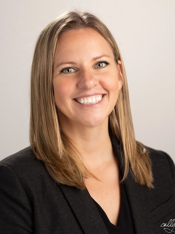 Professional portrait of a smiling woman with blonde hair in a black blazer.