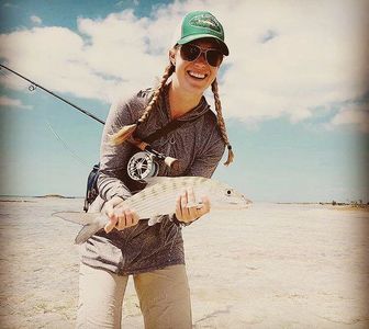 Woman holding a fish during a fishing trip.