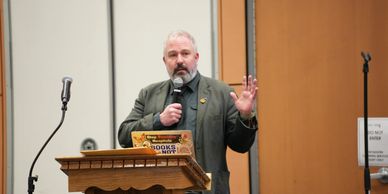 Speaker delivering a presentation with a microphone at a podium.
