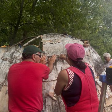 Two people applying bark to a tree trunk.